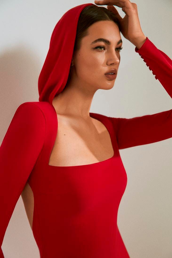 Mulher a usar um vestido comprido vermelho com capuz e um decote quadrado
