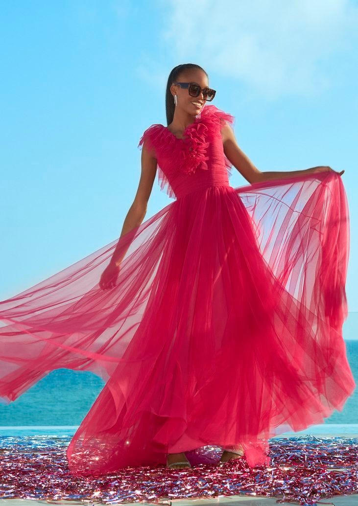 Woman with high ponytail and sunglasses wearing a pink tulle cocktail dress with a V neckline