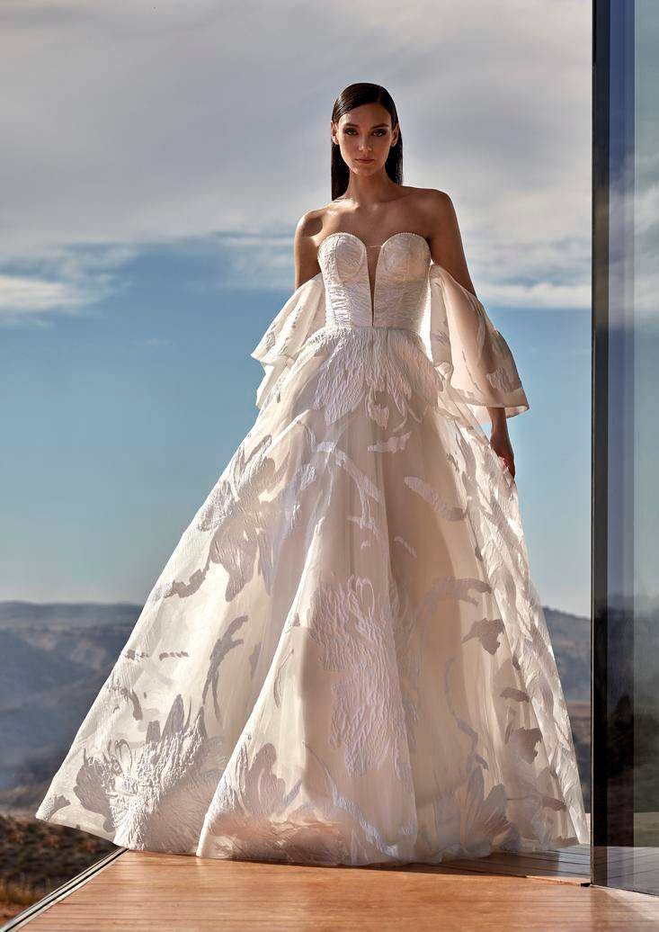 Une mariée dans une robe de mariée princesse moderne, bustier, dotée de manches évasées délicates et d'une jupe volumineuse