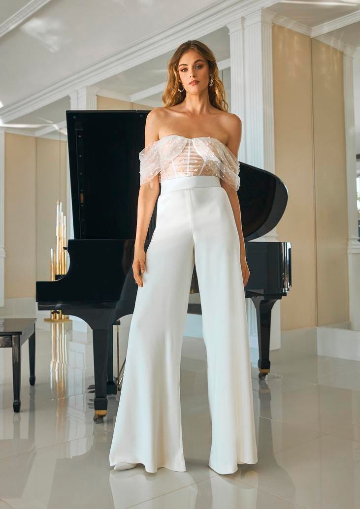 Modella che indossa un abito per matrimonio in comune con spalline cadenti e pantalone bianco elegante.