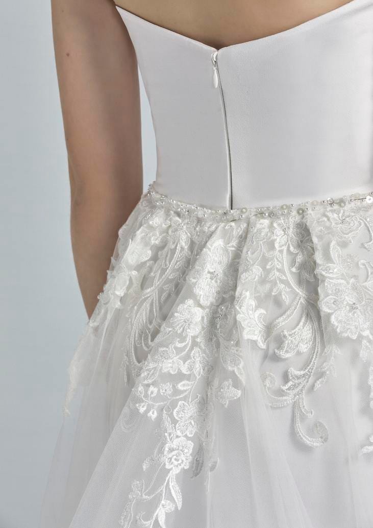 Detalle ampliado de un vestido de novia donde se ve la cintura y la cremallera de la prueba del vestido