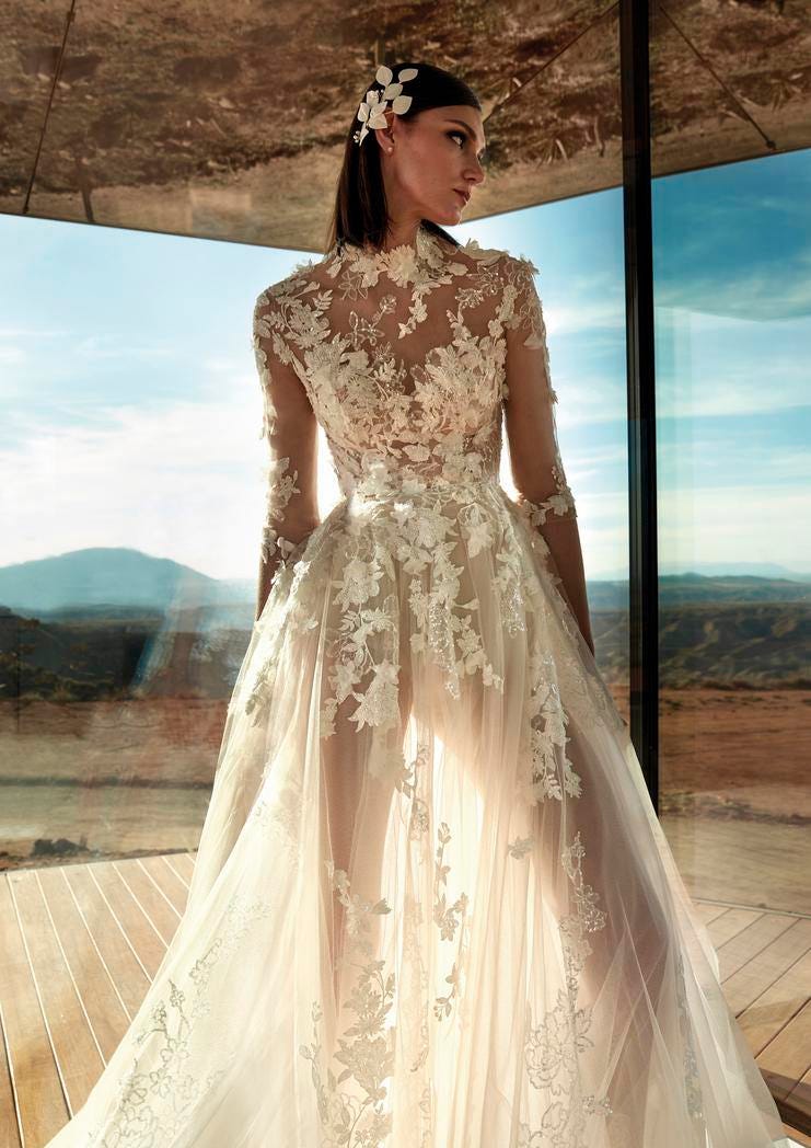 Modelo usa vestido de noiva com flores  3d bordadas e transparências ao longo de todo o vestido linha A e do decote em V complementado por toucado floral