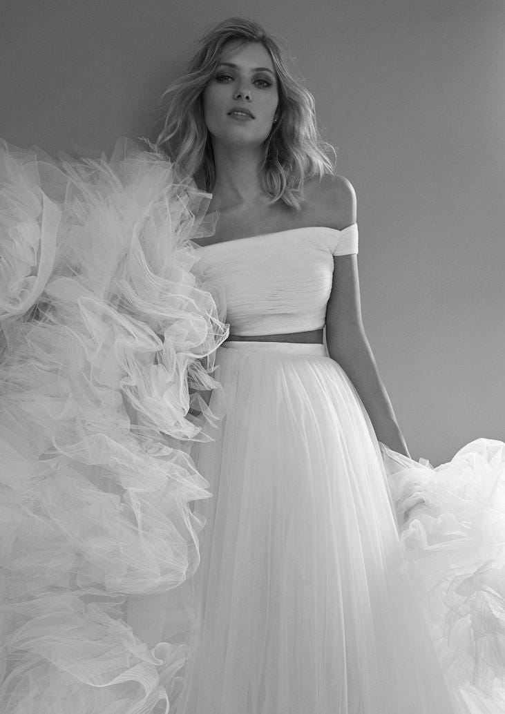 Woman wearing a two-piece bridal outfit with an off-the-shoulder top and a tulle skirt. 