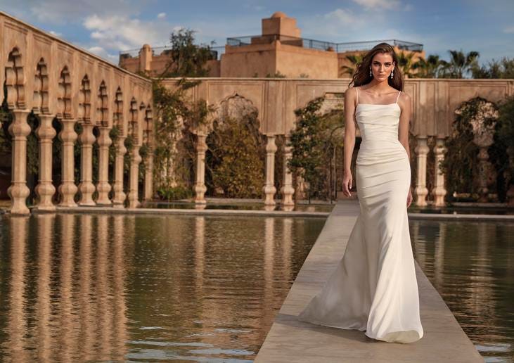 Woman wearing a simple wedding dress in satin with a square neckline and drop earrings.