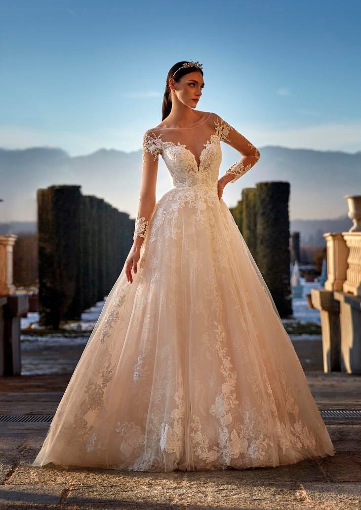 Une robe de mariée luxueuse à manches longues, conçue avec de la dentelle et du tulle, évoquant l'élégance et la grâce.