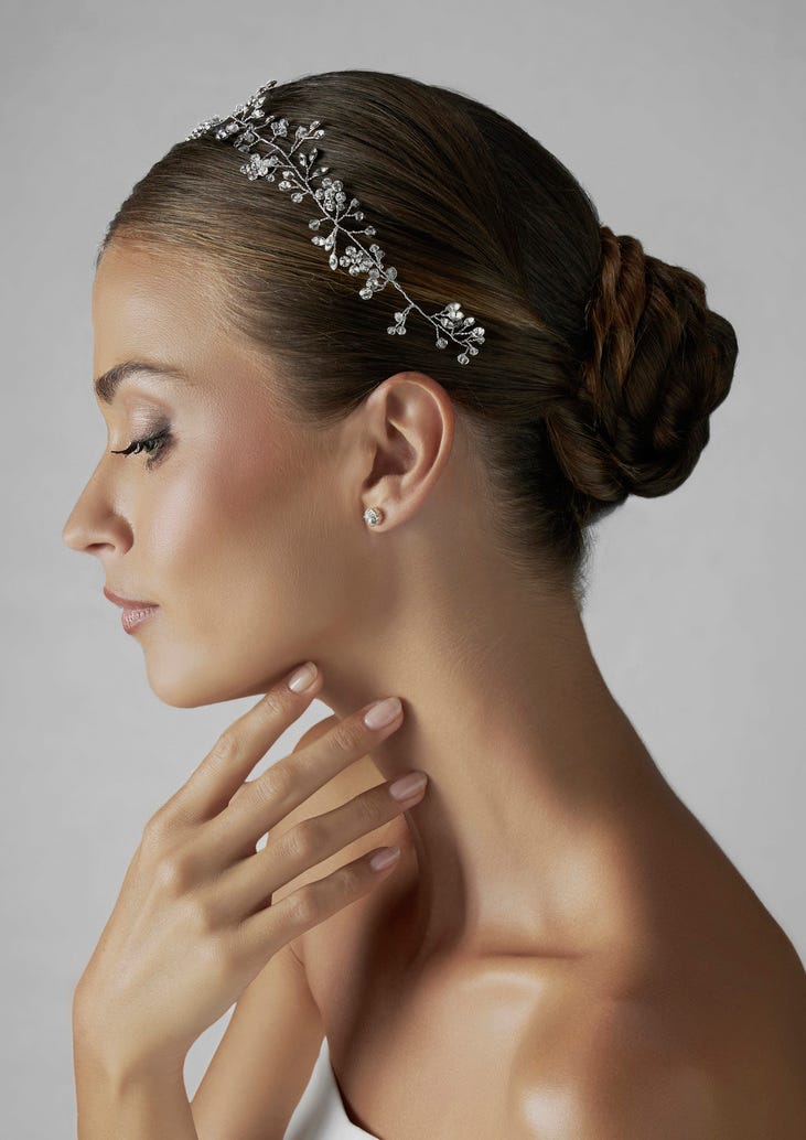 Frau mit Haarschmuck und Hand an dem Gesicht mit natürlichem Braut Nageldesign 