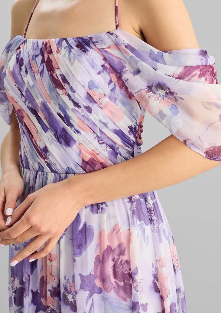 Frau in lila geblümten Kleid stehend mit hellem Nageldesign