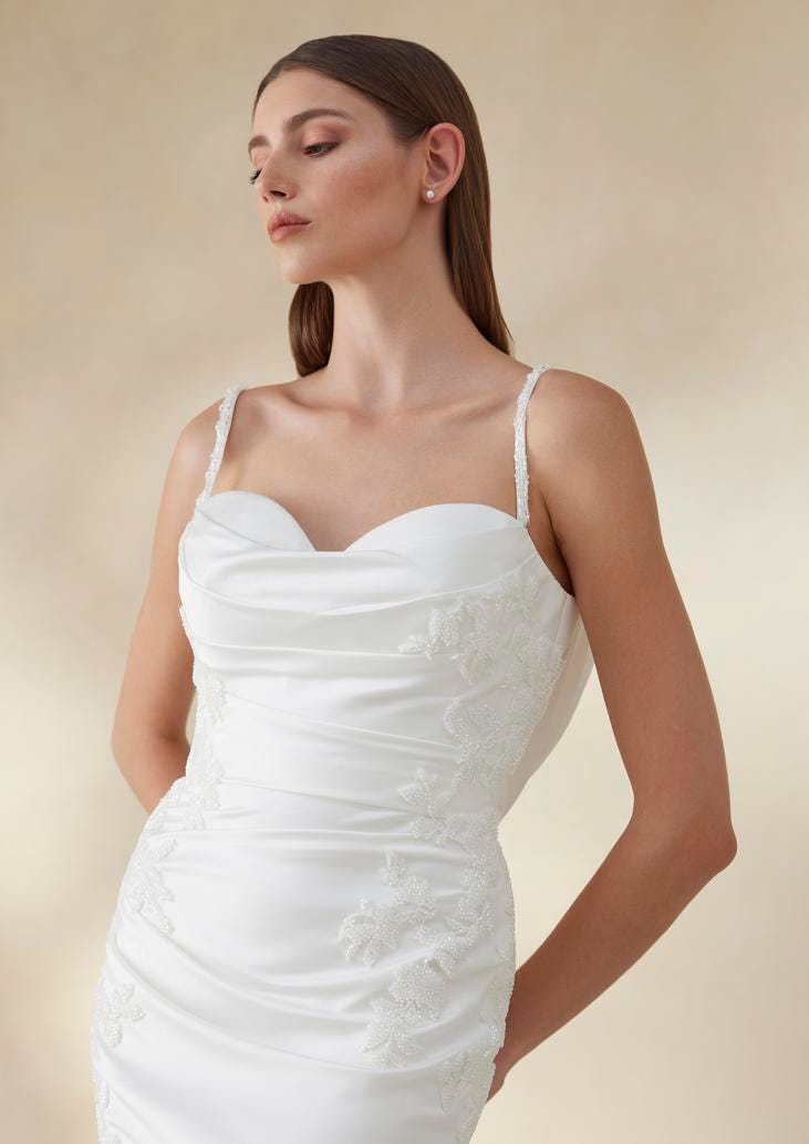 Frau in kurzem sportlichen Brautkleid in weiß mit Stickerein und dünnen Trägern nach unten schauend