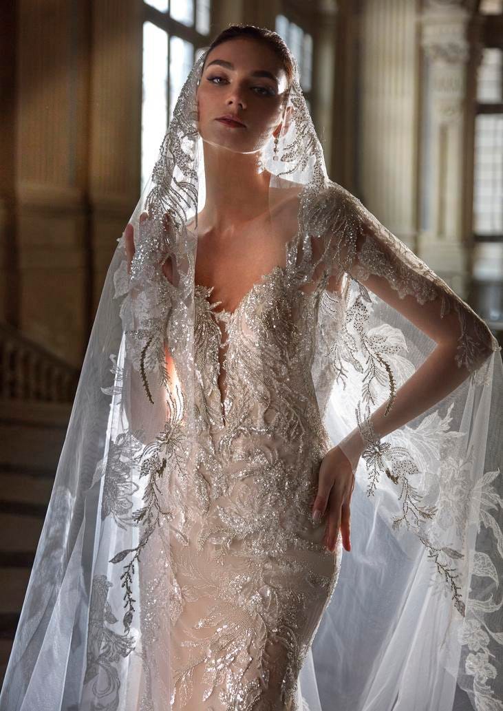 Woman wearing a mermaid wedding gown with sparkly embroidery, paired with a detachable sheer veil